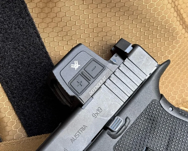 Close-up view of the side-facing illumination adjustment buttons on the Vortex Defender-ST Enclosed Solar optic housing