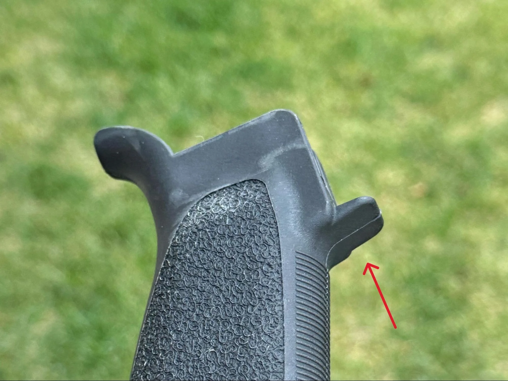 A photo demonstrating the potential issue of an extended forward tang on an AR-15 grip, possibly interfering with specific types of trigger guards