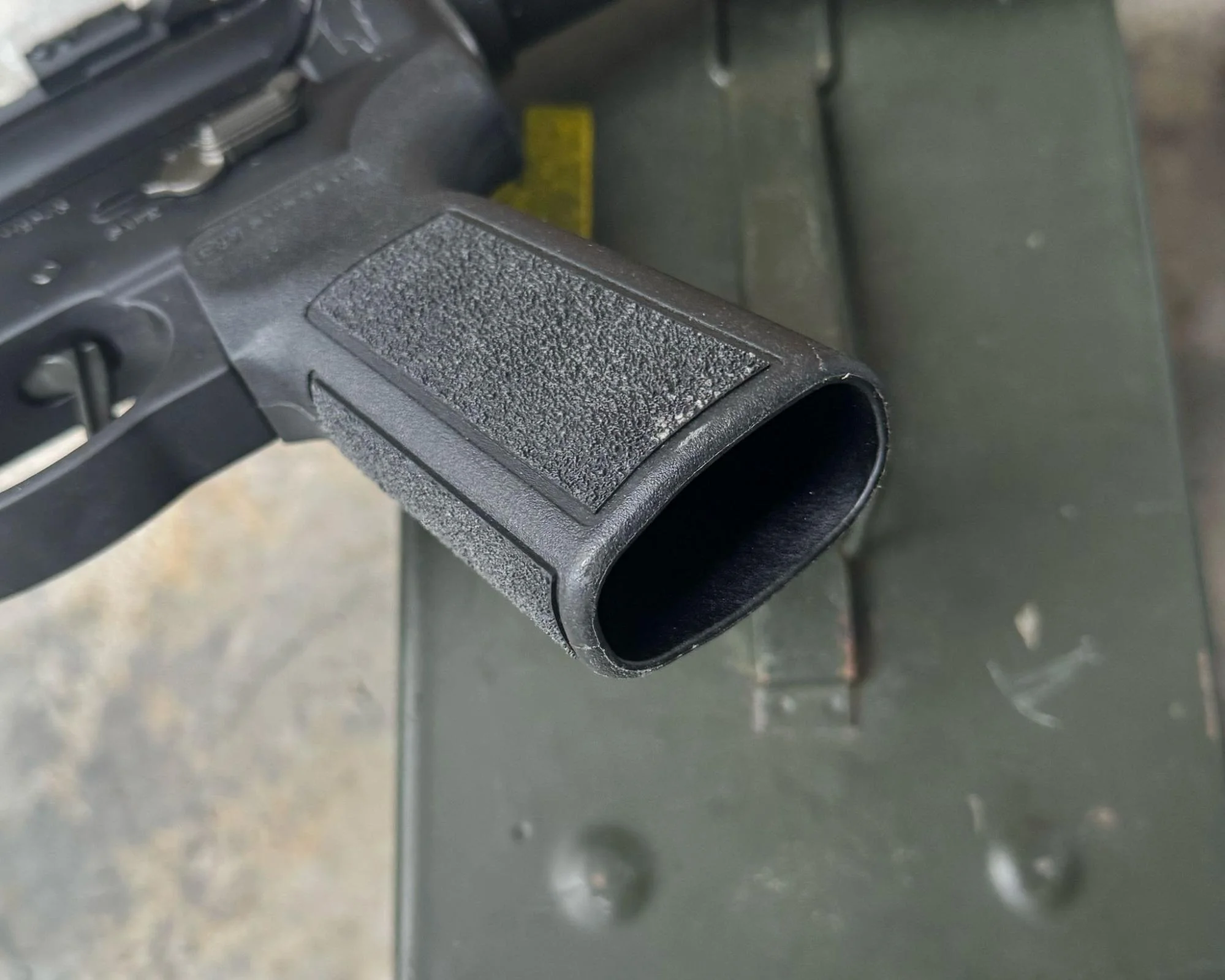 A photograph of an AR-15 grip without a grip plug, emphasizing the incomplete appearance and the need for the accessory
