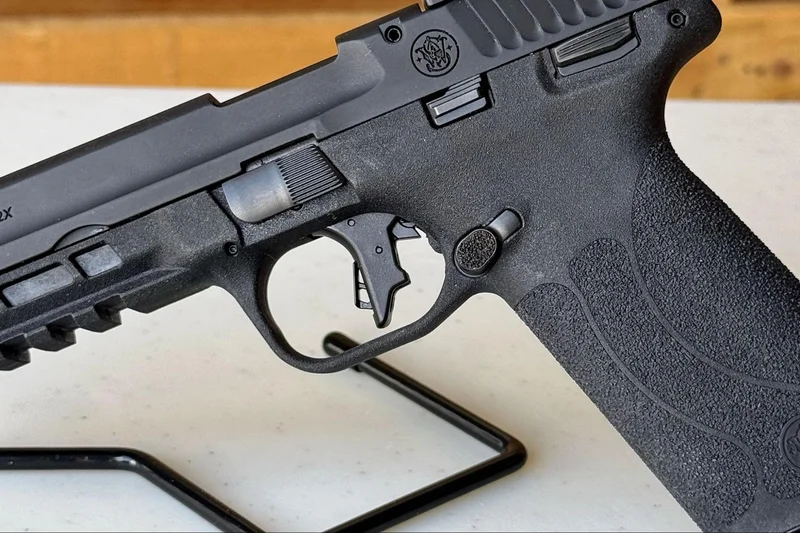 Close-up of the Smith & Wesson M&P22X flat-face trigger and textured frame magazine release
