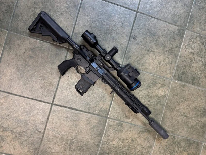 Pulsar Thermion 2 LRF XL60 on a suppressed Liberty Bell AR-15 lying on a tile floor