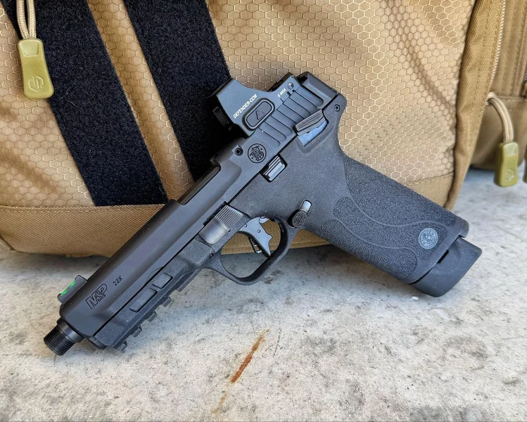 Smith & Wesson M&P22X rimfire pistol with mounted red dot optic resting on a tan range bag