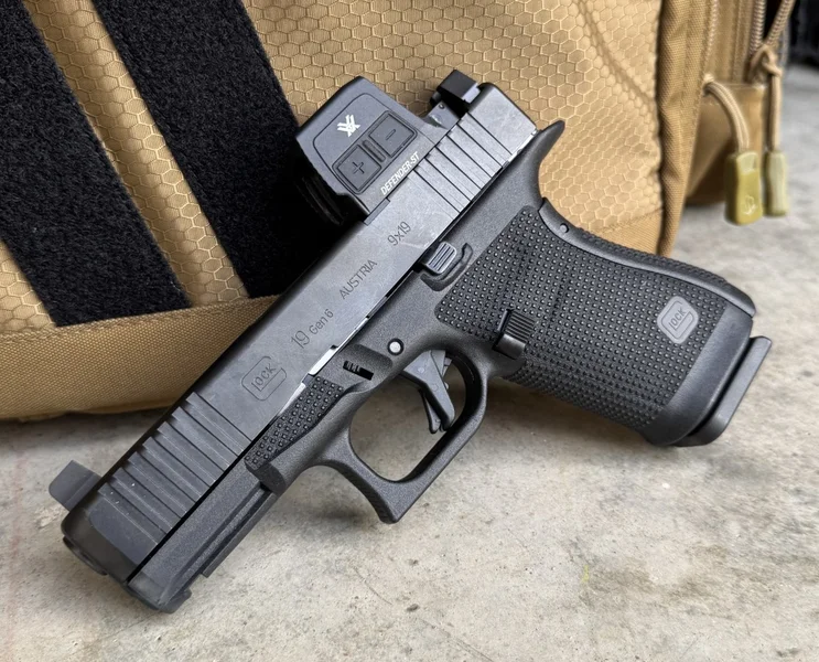 Vortex Defender-ST Enclosed Solar optic mounted on a Gen6 Glock 19 pistol resting against a tan tactical bag