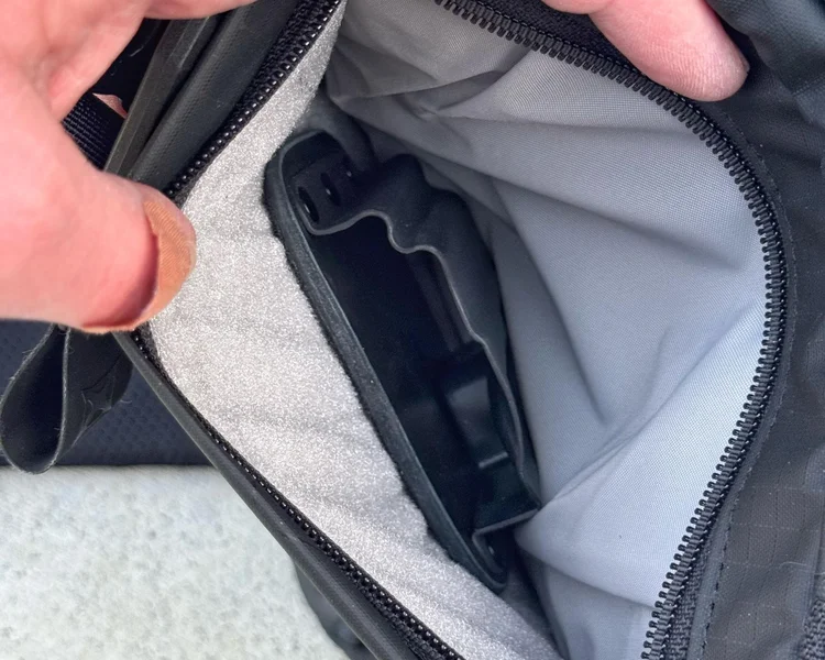 Close-up of the concealed carry pocket inside the VERTX sling bag with a holster secured in place