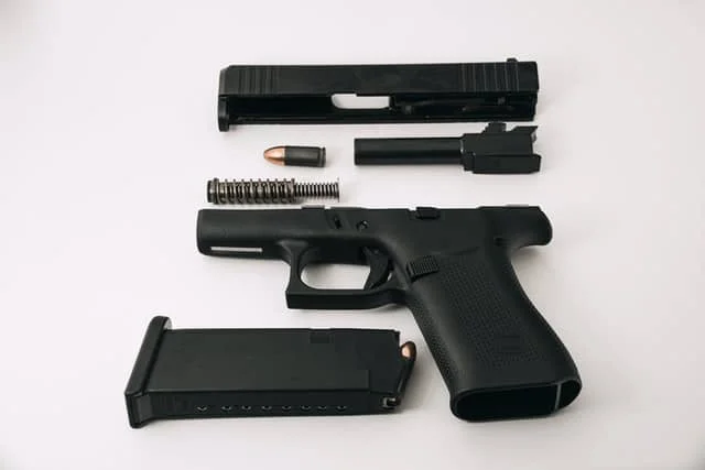Disassembled Glock G43X (barrel, guide rod, and slide removed), loaded magazine, and 9mm round.