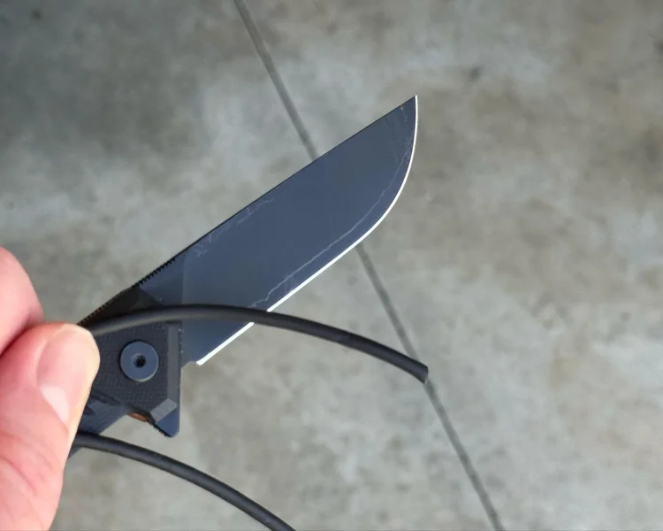 Tekto F1 Alpha EOTECH knife cutting through an old black charging cable