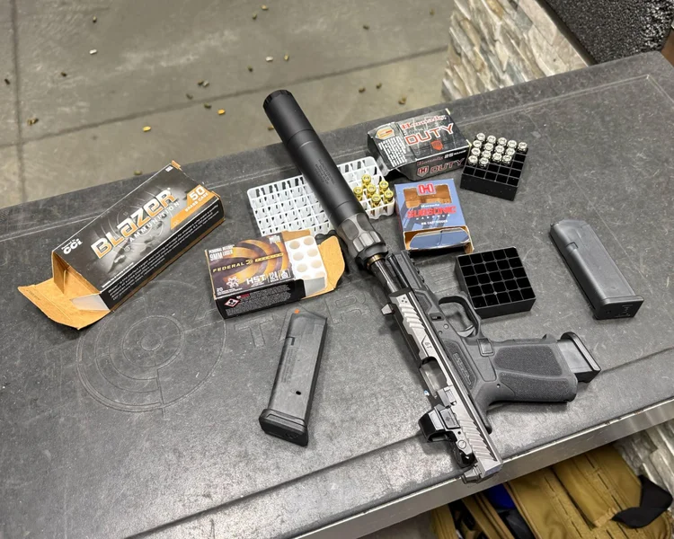 Suppressed Strike Arms pistol on a range table with Blazer Brass, Hornady Critical Duty, and Federal HST 9mm ammunition.